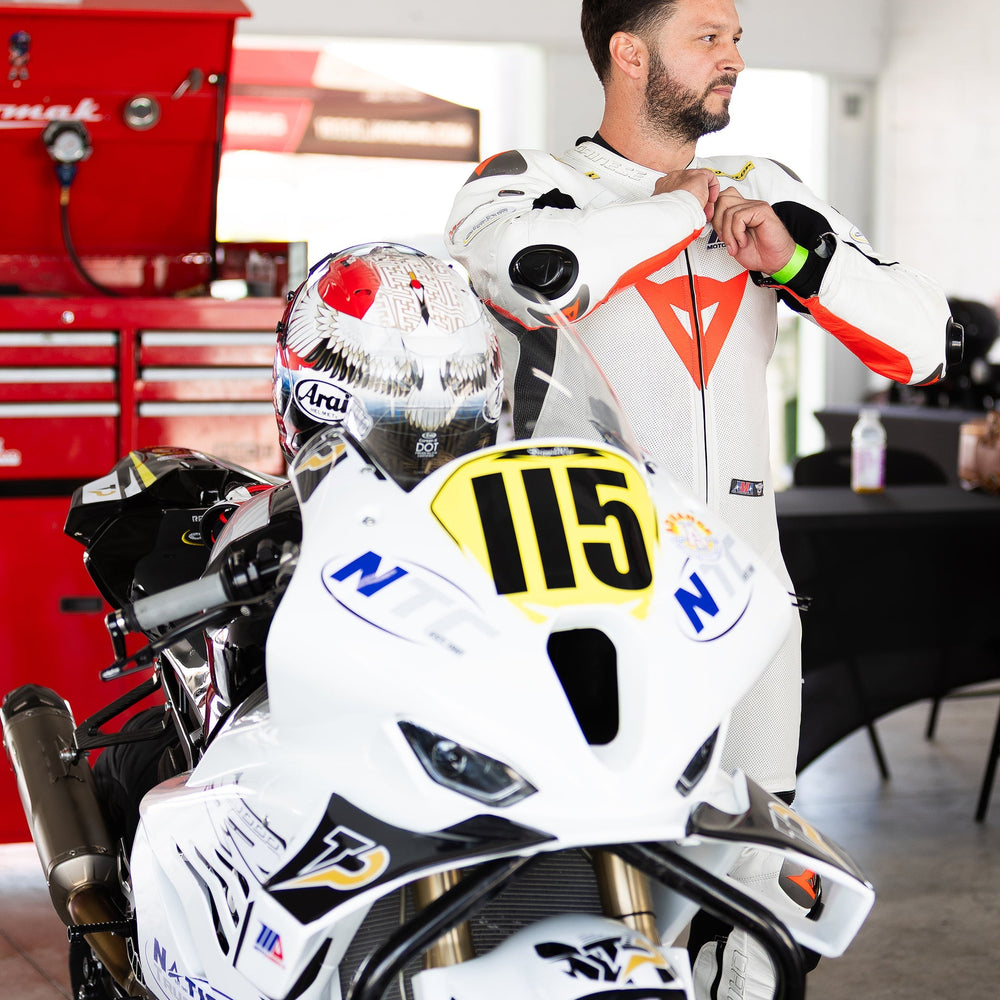 Motorcycle rider in full race gear leans into a turn at Homestead-Miami Speedway during a track day in South Florida