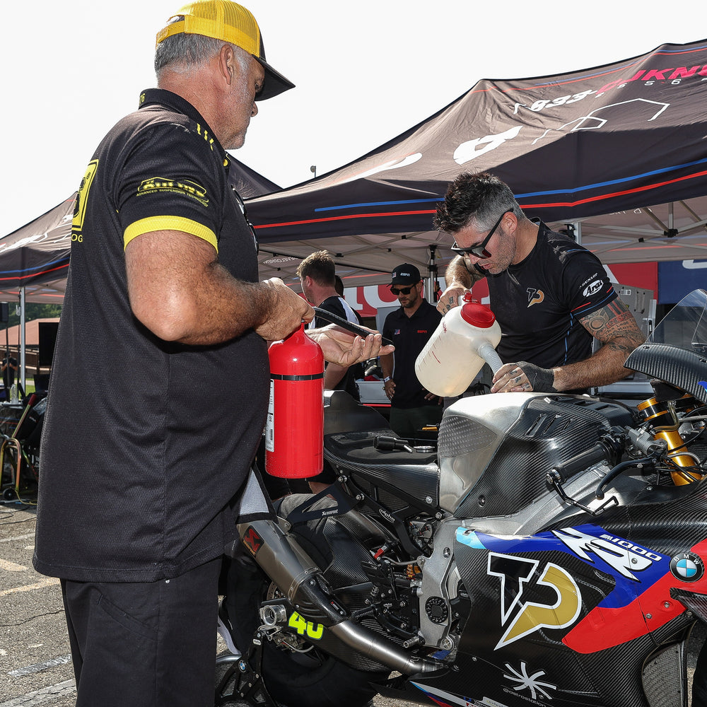 Motorcycle rider geared up and ready to ride on a race track in South Florida, with a support crew from Top Pro Motorsports.